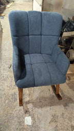 A blue upholstered rocking chair with a high back and wooden rockers, photographed in a workshop.