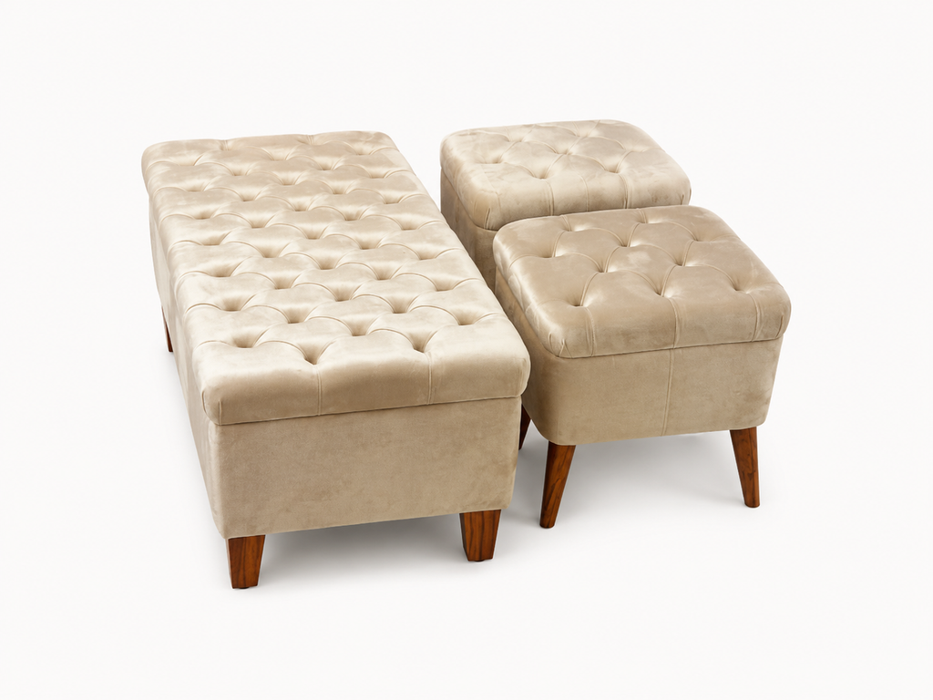 A set of three tufted storage ottomans in a warm beige velvet fabric with dark brown wooden legs, shown on a clean white background.