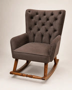 A classic wingback armchair with a tufted button-back high backrest, upholstered in a textured brown fabric, supported by a warm brown wooden rocking base.