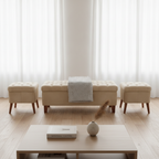 A staged interior scene with a tufted bench centered between two matching ottomans on a light wood floor, in front of sheer white curtains. A low wooden coffee table with a small vase and book sits in the foreground.