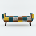 A modern patchwork bench with a colorful upholstered seat and backrest, featuring teal velvet, mustard yellow, brown, and marble-patterned panels, supported by dark wooden legs on a light gray background.