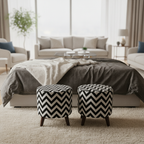 Two round upholstered ottomans with a black and white chevron pattern and dark wooden legs, placed in front of a bed in a bright, modern bedroom.