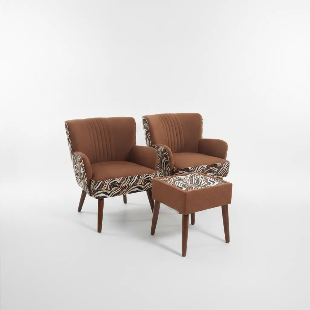A pair of mid-century modern armchairs with matching ottoman, upholstered in rust brown fabric with zebra-patterned armrests and dark wood legs, photographed on a seamless white studio background.